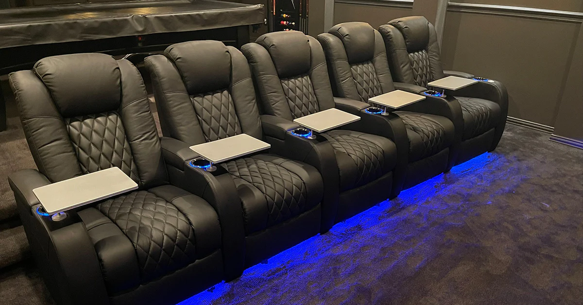 Row of luxury home theater seats with LED base lighting, swivel tables and premium leather upholstery design