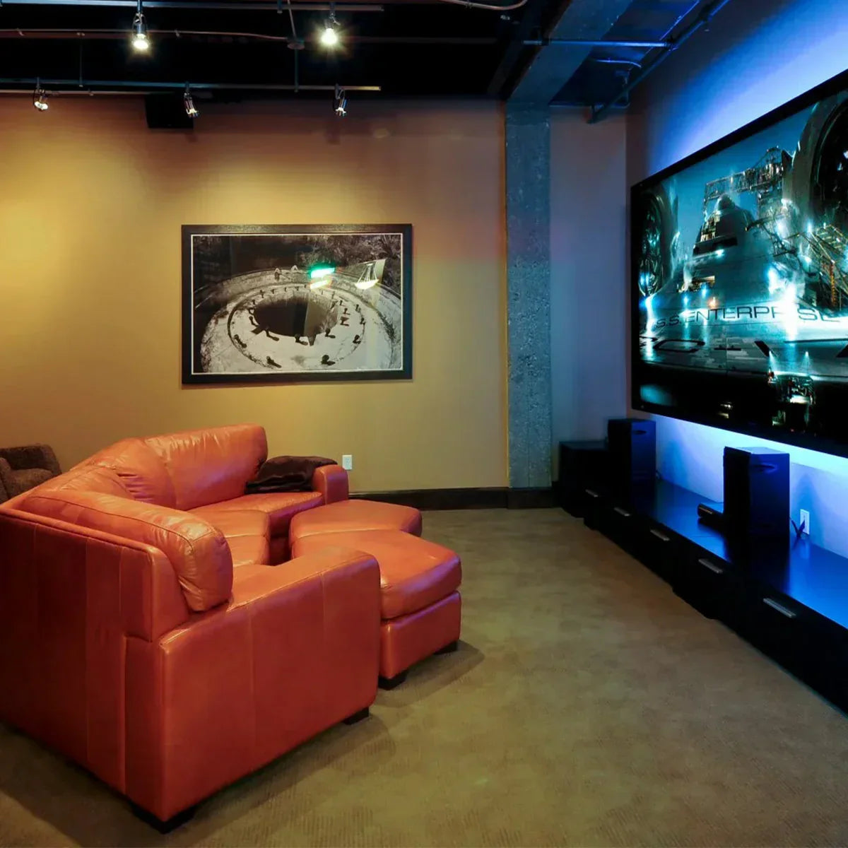 A modern home theater with a comfortable orange leather sofa facing a large screen.