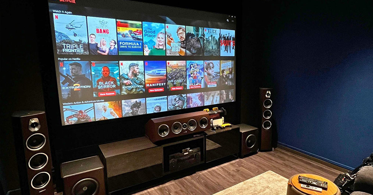 Dedicated media room with large projector screen and surround speakers on dark walls.
