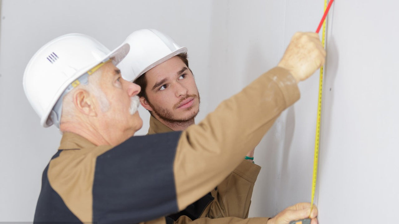 The image shows two construction workers wearing hard hats.