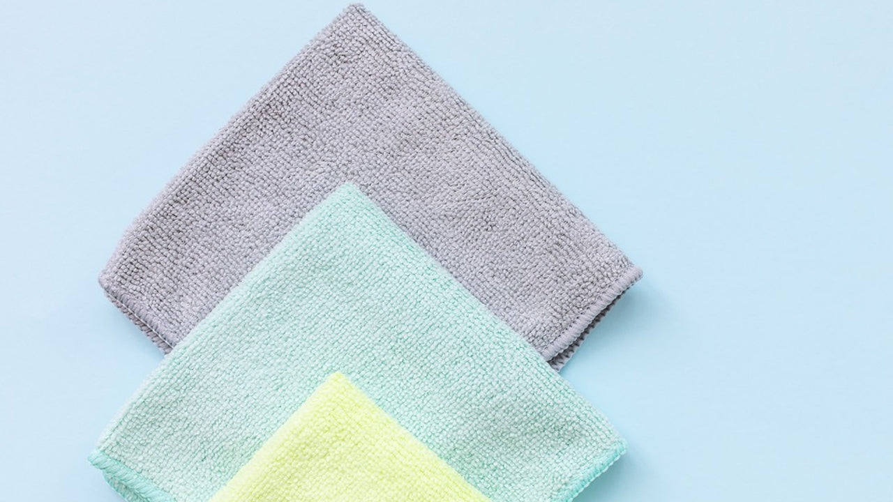 Three microfiber cloths in different colors, essential for blotting, wiping, and cleaning leather theater seats during the stain - removal process. 