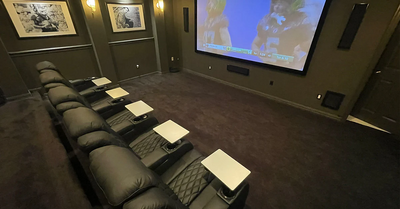 Luxury home theater room with multiple reclining seats tray tables and large screen for family movie marathons