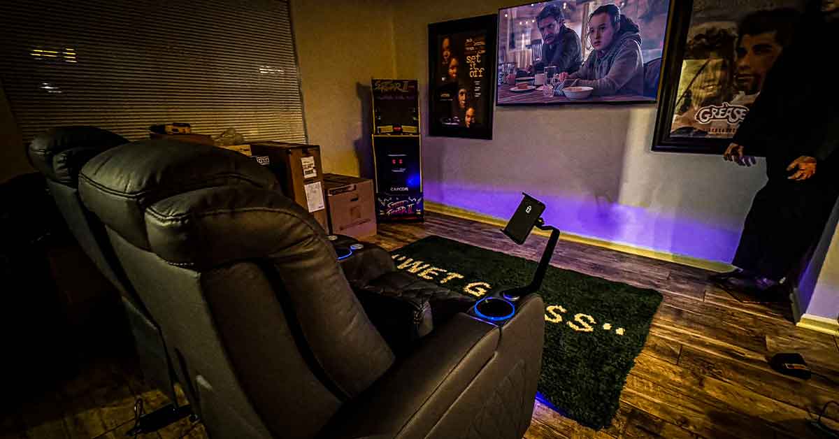 Complete home theater room setup with reclining chair, large TV screen, gaming console and ambient LED strip lighting