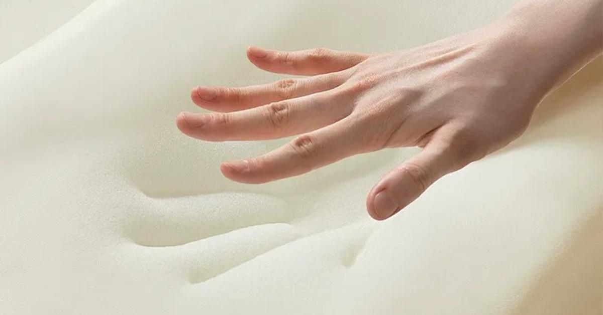 Hand pressing into memory foam, showing slow response and contouring