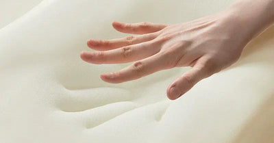 Hand pressing into memory foam, showing slow response and contouring