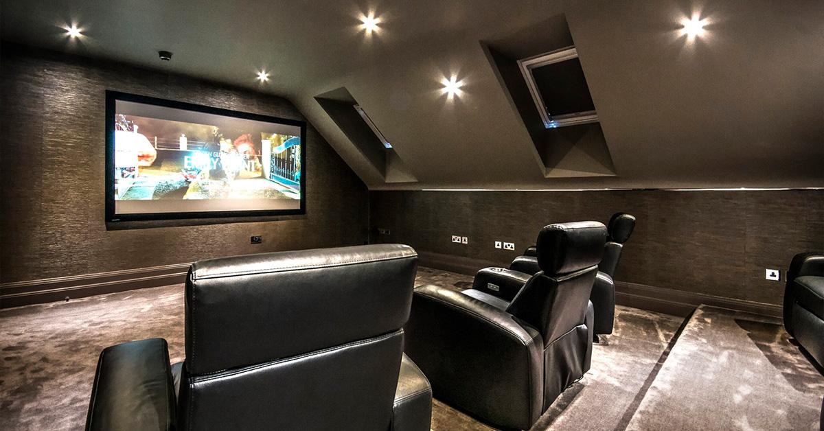 Cozy attic home theater with sloped ceiling and black leather recliner seating