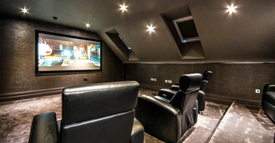Cozy attic home theater with sloped ceiling and black leather recliner seating