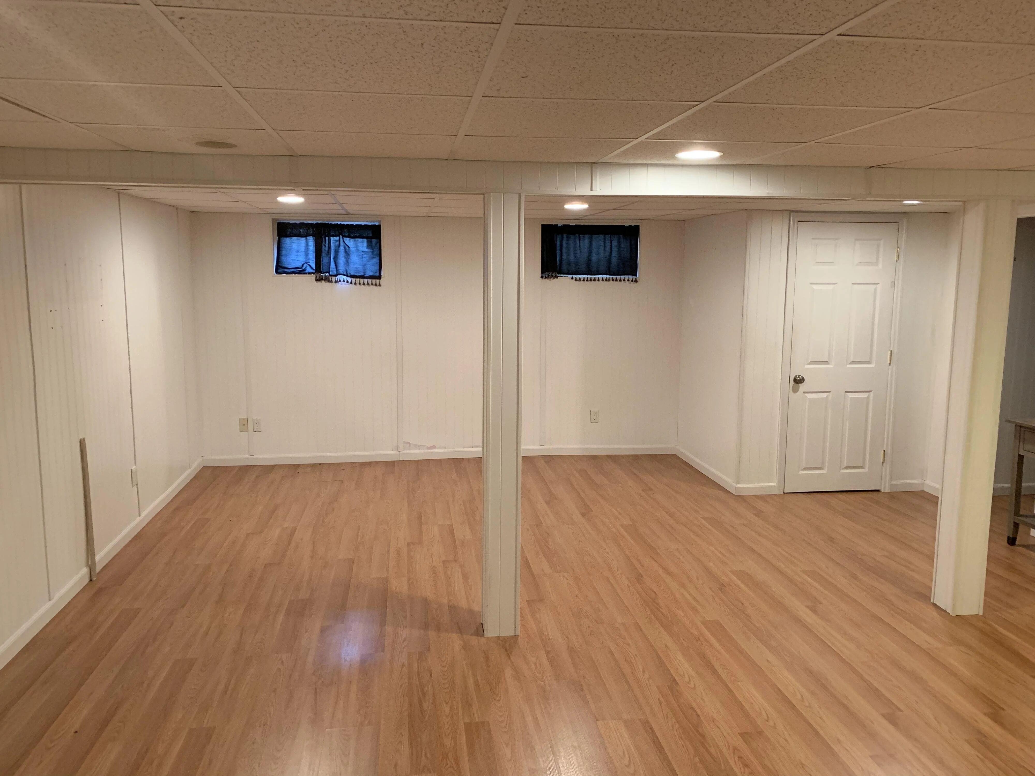Unfinished basement with wood flooring and white walls, ideal for renovation