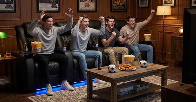 Friends cheering in home theater recliners during soccer watch party