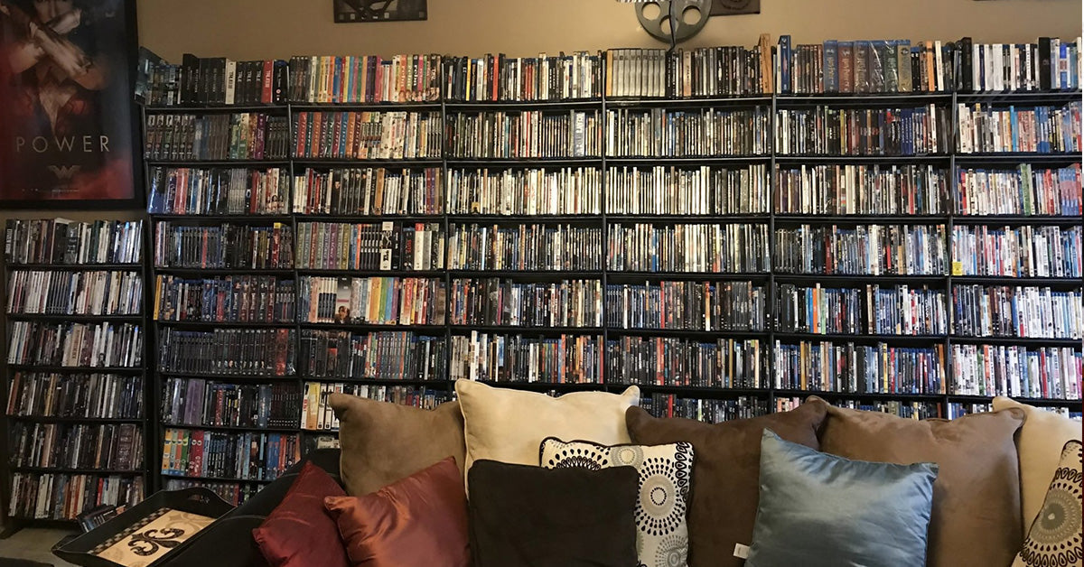 home media room with wall-to-wall DVD and Blu-ray shelves behind a couch