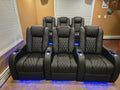 Front row of black home theater recliners with blue LED base lighting