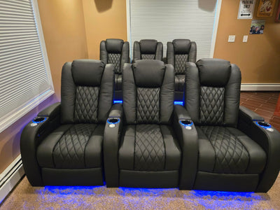 Front row of black home theater recliners with blue LED base lighting