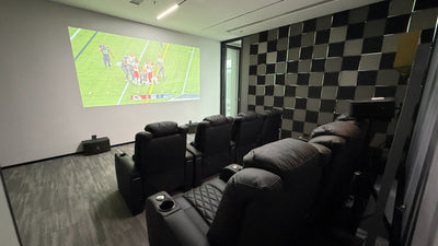 Private screening room with recliner seating and sports game projected on wall