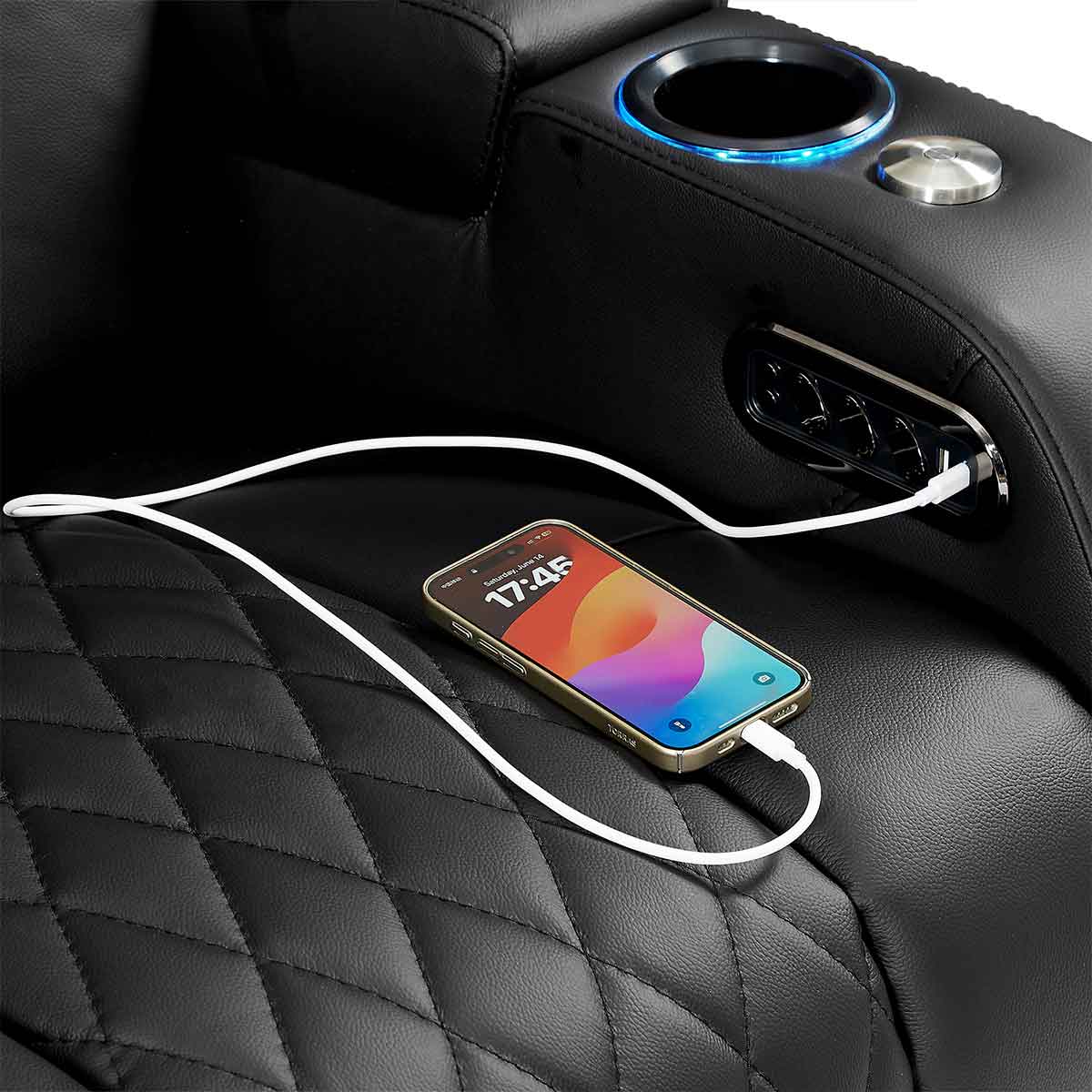 Phone charging from a USB port on a black leather recliner.