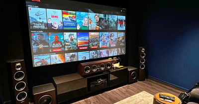 Dedicated media room with large projector screen and surround speakers on dark walls.